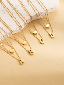 Detailed macro view of four gold-plated titanium steel necklaces with A-D initial pendants