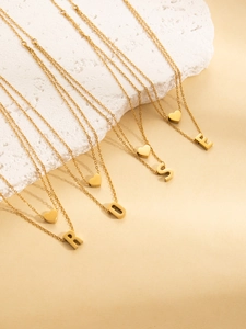 Detail view of double-layered gold-plated necklaces with heart and ROSE letter charms