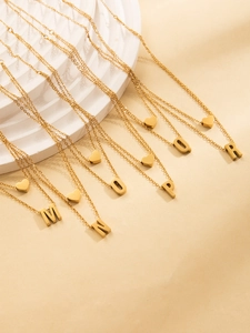 Macro shot of gold-plated heart and initial letter pendants on stainless steel chains