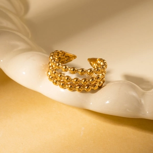 Macro shot of gold three-layer bead ring with adjustable open band on ceramic tray