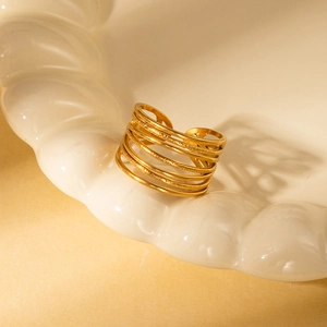 Macro shot of gold layered wrap ring with mixed textures on a white ceramic tray