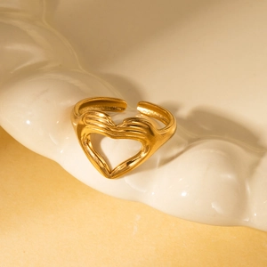 Macro shot of gold adjustable ring featuring a creative heart gesture design on ceramic