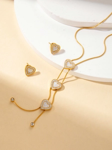 Dettaglio del set di gioielli a cuore dorato con inserto in conchiglia e strass lucidi