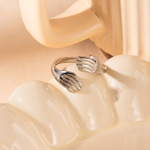 Detalle de anillo de abrazo en acero inoxidable plateado sobre fondo de cerámica