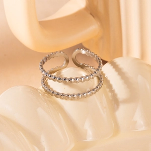 Detailed close-up of a double-layered silver beaded open ring on a ceramic plate