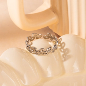 Macro shot of silver olive leaf open ring on a wavy textured display base