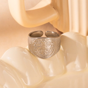 Close-up of silver St. Benedict medal ring with vintage cross details on a ceramic tray