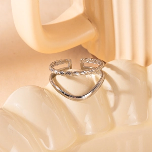 Detalle de anillo plateado ajustable con textura trenzada en soporte de cerámica