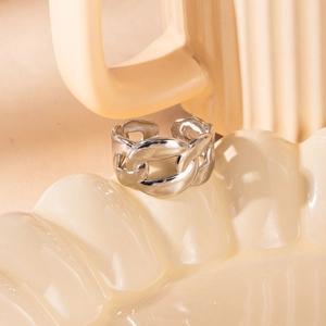 Detalle de anillo de cadena de eslabones plateado sobre superficie de cerámica crema