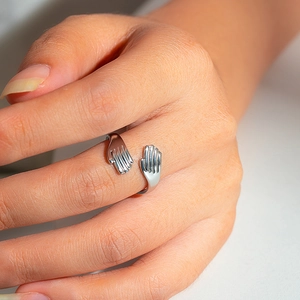 Detalle del anillo de abrazo en acero inoxidable plateado con diseño de palma y brillo