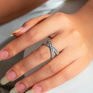 Detailed macro view of beaded silver cross X-shaped ring on model finger
