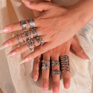 Dettaglio di anelli stile boho argento con stella e moneta su seta dorata calda