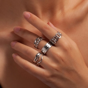Dettaglio di un set di quattro anelli geometrici in acciaio argento indossati sulla mano