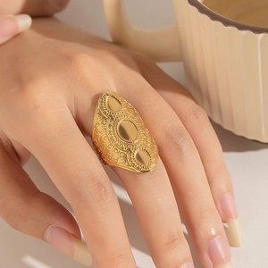 Détail d'une bague bohème en acier inoxydable doré avec gravures et surfaces métalliques