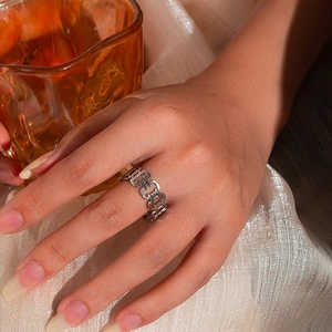 Dettaglio anello a catena geometrica argento su seta champagne con ombre eleganti