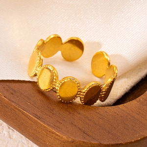 Détail de la bague ouverte dorée aux maillons ovales perlés sur un support bois