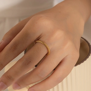 Bague torsadée en acier inoxydable doré au fini minimaliste portée à la main
