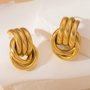 Gros plan de boucles d'oreilles en acier doré 18 carats avec un design de nœud torsadé