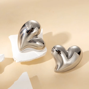 Macro shot of silver heart studs with polished mirror finish on white stone base