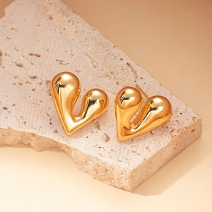 Detail of 18K gold plated stainless steel heart earrings on a textured stone base