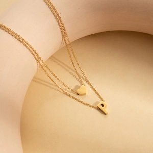 Close-up of double-layer gold necklace featuring a heart charm and letter P pendant