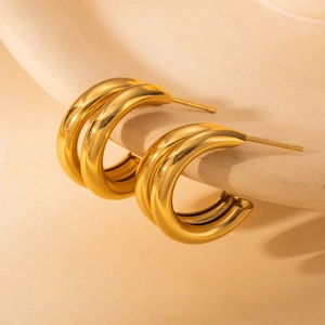 Boucles d'oreilles créoles C en acier inoxydable doré sur un plat en céramique