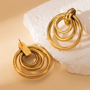 Makro-Detail von dreilagigen goldenen Creolen mit poliertem Goldfinish und Ohrsteckern