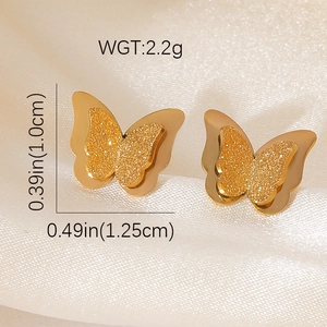 Détail macro de boucles d'oreilles papillon dorées montrant les dimensions et la finition