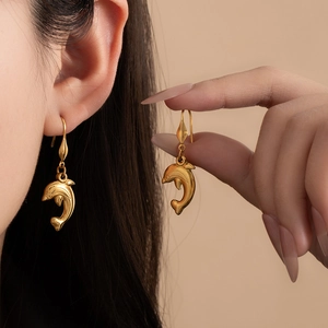 Close-up of model wearing gold dolphin-shaped earrings with a matte metallic finish
