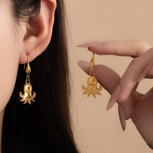 Detail of octopus earrings in matte 18K gold finish on model's ear and hand