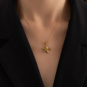 Close-up of a gold starfish pendant necklace on a woman wearing a black blazer