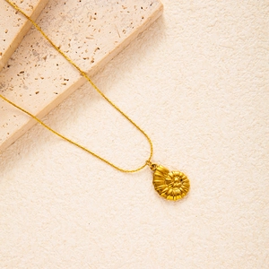 Macro detail of golden nautilus shell pendant with matte finish on textured stone background