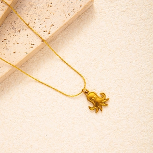 Close-up of gold-plated titanium octopus pendant with fine texture on dainty cross chain