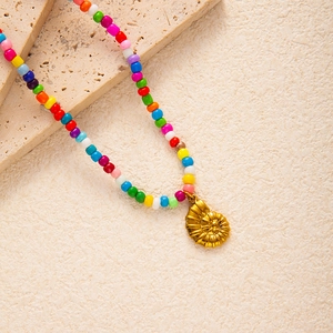 Detailaufnahme der bunten Perlenkette mit goldenem Nautilus-Anhänger auf Steinoptik