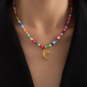 Detail einer bunten Boho-Perlenkette mit goldenem Delfin-Anhänger an einem Model