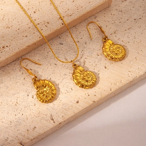 Detailed view of golden nautilus shell jewelry set on travertine stone background