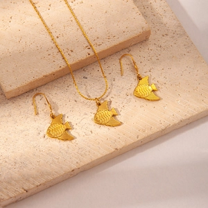 Detail shot of golden tropical fish jewelry set with necklace and earrings on stone