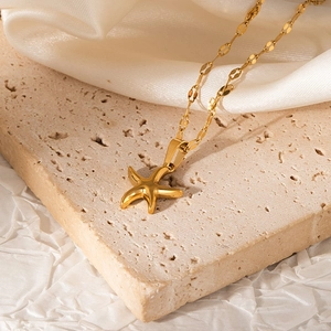 Detail of a polished golden starfish pendant with a shimmering flat link necklace chain