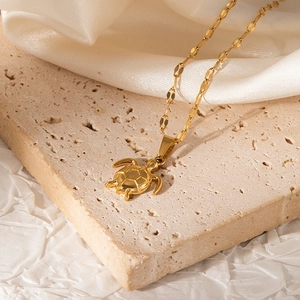Close-up of golden sea turtle pendant with geometric shell pattern on a delicate chain