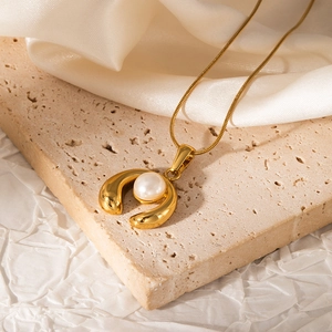 Detail of 18K gold plated snake chain necklace with pearl pendant on elegant background