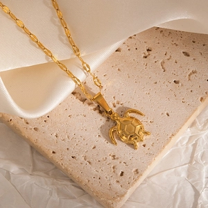 Detailed view of a gold turtle pendant necklace on a premium textured stone surface