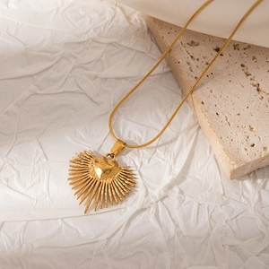 Dettaglio della collana con pendente a cuore dorato su sfondo in pietra naturale
