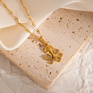 Detail of a polished golden octopus pendant necklace on a premium textured stone background