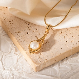 Macro detail of 18K gold-plated snake chain necklace with organic pearl pendant