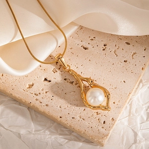 Macro detail of 18K gold-plated irregular branch pendant with a round white pearl inlay