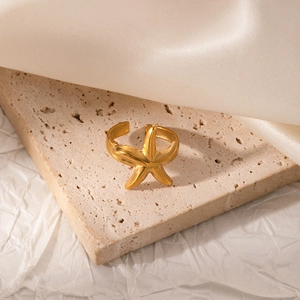 Detailed close-up of matte gold starfish ring on elegant beige stone and silk background