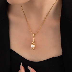 Macro shot of 18K gold plated necklace with a pearl pendant and sleek snake chain link