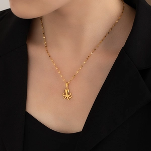 Close-up of a stylish gold-tone octopus pendant necklace worn by a model on black clothing