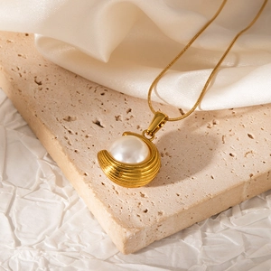 Close-up of 18K gold plated pearl pendant with wavy textured base on a fine snake chain