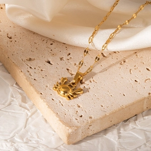 Detail of a golden crab pendant necklace displayed on a textured stone pedestal